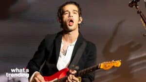 Musician Matthew Healy playing a red Fender guitar during a live performance