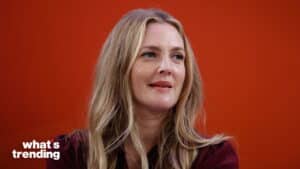 Blonde woman with long hair speaking against an orange background with "what's trending" text.