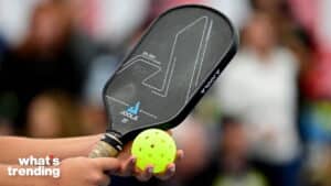 Hand holding a JOOLA Hyperion pickleball paddle and a yellow perforated pickleball.