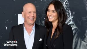 Bruce Willis and Emma Heming smiling together at a public event with a dark backdrop.