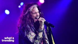 Steven Tyler passionately singing on stage with purple and blue lighting