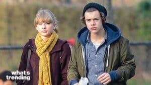 Taylor Swift wearing a yellow scarf and Harry Styles in a green jacket and black beanie walking outdoors