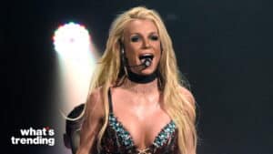 Britney Spears performing on stage wearing a jeweled outfit and headset microphone with spotlight behind her