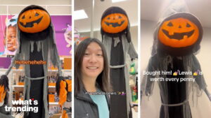 Person posing with a tall Halloween decoration named Lewis, a pumpkin-headed figure in tattered gray robes.