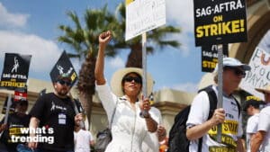 Protesters holding SAG-AFTRA on strike signs during a labor strike outdoors with palm trees in background