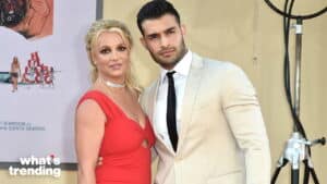 Britney Spears in a red dress and Sam Asghari in a beige suit posing together at a red carpet event.