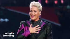 Singer Pink smiling with hand on chest wearing a black and purple jacket during a performance