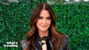 Kyle Richards smiling in front of a green hedge wall with "what's trending" text in the corner