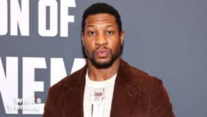 Jonathan Majors holding a Critics Choice Award at a film event with a gray backdrop.