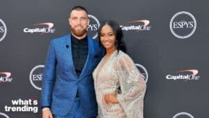 Man in blue patterned suit and woman in sheer silver dress posing at the ESPYS event with Capital One branding