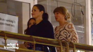 Selena Gomez and Taylor Swift walking together indoors near a railing at night