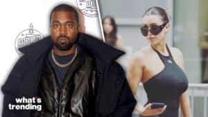 Kanye West in black jacket and gold chain next to Kim Kardashian in black halter top and sunglasses holding phone outdoors