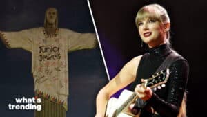 Taylor Swift playing guitar on stage next to the Christ the Redeemer statue wearing a Junior Jewels poncho