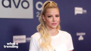 Blonde woman with long wavy hair in a white top posing at Bravo event backdrop