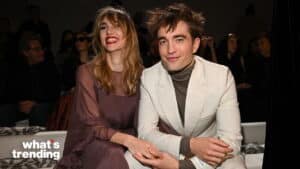 Actors Robert Pattinson and Suki Waterhouse smiling and holding hands at a fashion event
