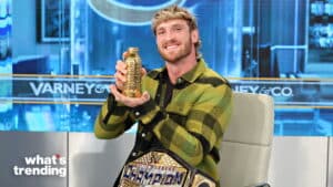 Logan Paul holding a golden trophy with a WWE United States Champion belt on his lap on Varney & Co. set.