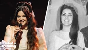 Lana Del Rey singing on stage and smiling in a vintage wedding dress and veil in a black and white photo.