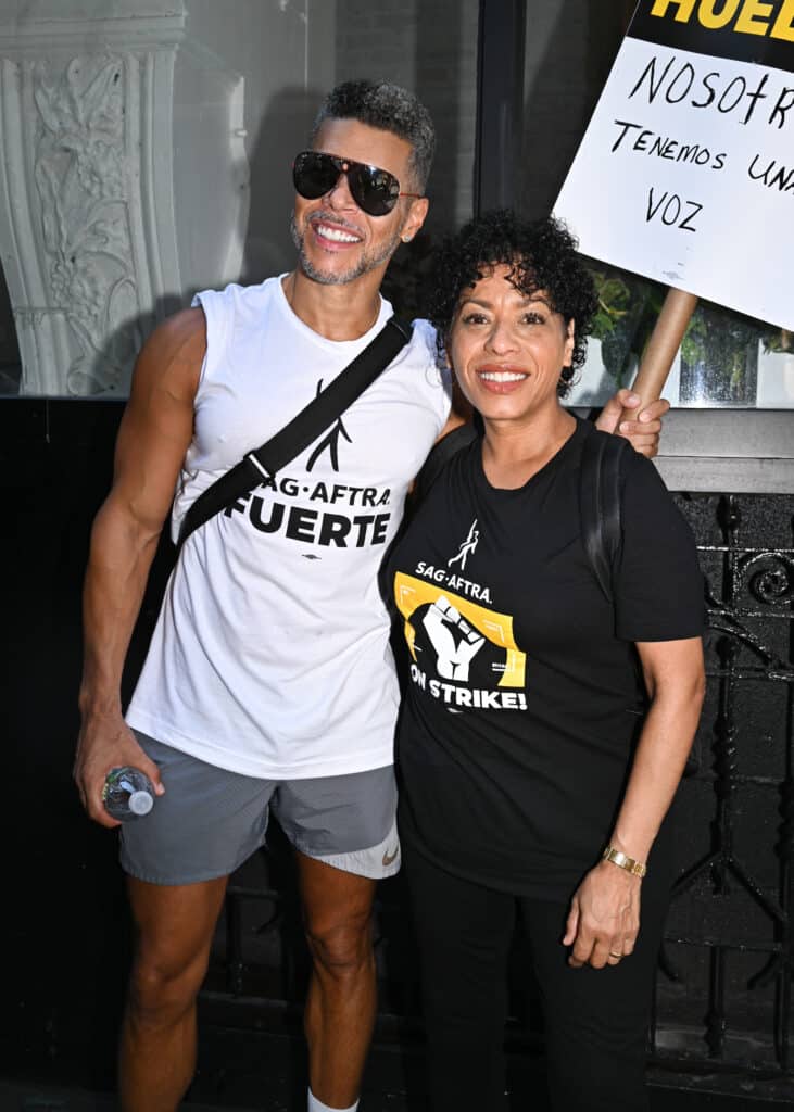 Wilson Cruz and Liza Colon-Zayas walk the picket line in support of the SAG-AFTRA and WGA strike outside Warner Bros. Discovery Headquarters on August 18, 2023 in New York City.