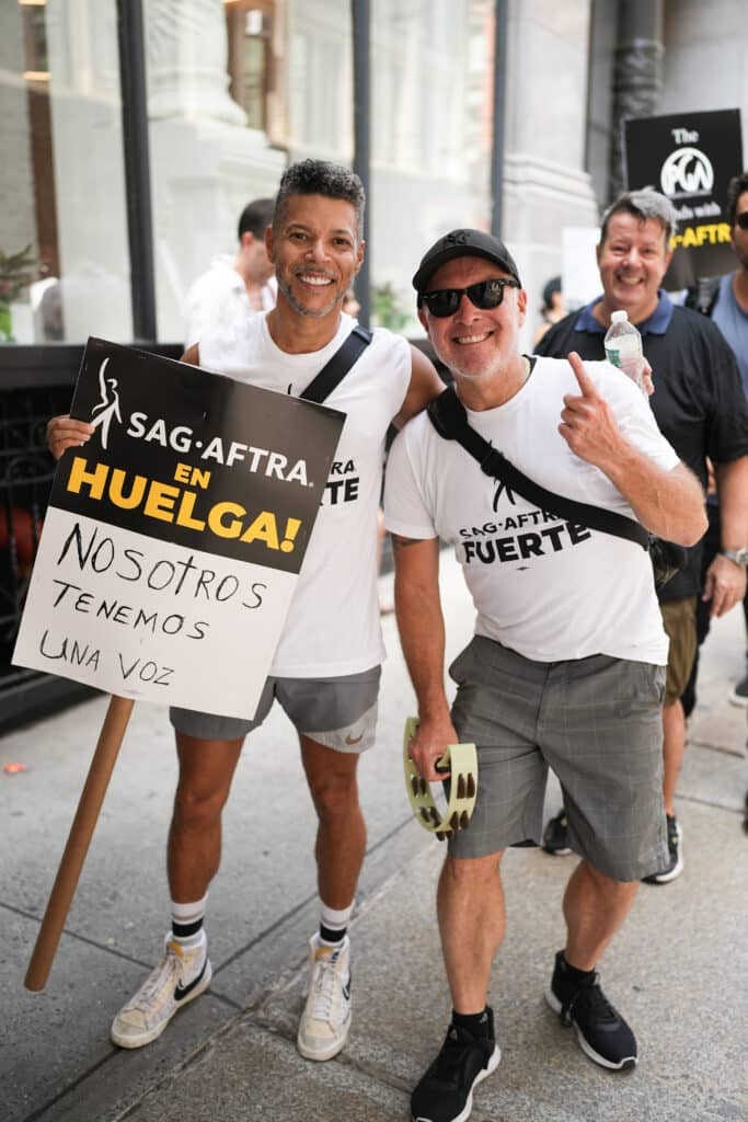 Wilson Cruz (L) joins SAG-AFTRA members as they maintain picket lines in front of NBCUniversal on August 18, 2023 in New York City. Members of SAG-AFTRA and WGA (Writers Guild of America) have both walked out in their first joint strike against the studios since 1960. The strike has shut down a majority of Hollywood productions with writers in the third month of their strike against the Hollywood studios.