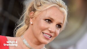 Britney Spears smiling with diamond earrings and a silver choker necklace at an event