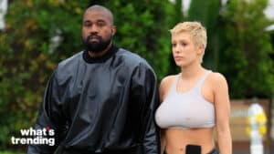 Kanye West in black outfit and Julia Fox in gray crop top walking outdoors.