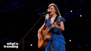 Taylor Swift performing live in a blue dress playing acoustic guitar on stage