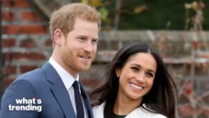 Prince Harry and Meghan Markle smiling outdoors near a brick wall