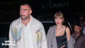 Taylor Swift and Travis Kelce walking together at night, Taylor wearing a black top and checkered coat, Travis in a white patterned jacket