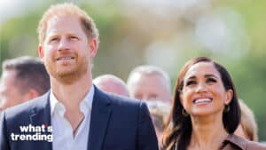 Prince Harry and Meghan Markle smiling outdoors with blurred crowd in background