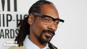 Snoop Dogg wearing glasses and a suit at a hip-hop awards event with "what's trending" logo.
