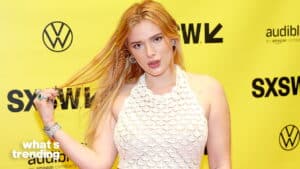 Bella Thorne posing on the yellow SXSW event backdrop wearing a white crocheted halter top.