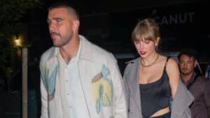 Man in white patterned jacket and woman in black corset top and checkered coat walking at night
