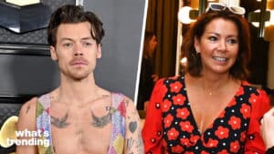 Harry Styles wearing a colorful sleeveless top next to a woman in a red and black floral dress smiling indoors.