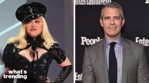 Madonna in a black latex outfit and hat speaking at a microphone, Andy Cohen in a gray suit at an Entertainment Weekly event