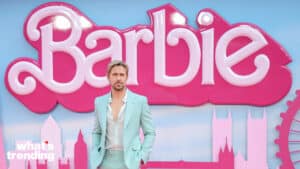 Ryan Gosling in a light blue suit at the Barbie movie premiere with a large pink Barbie logo backdrop
