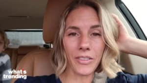 Woman with short blonde hair sitting in a car with a child in the backseat and "what's trending" text in the corner