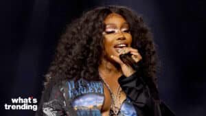 Singer SZA performing on stage with curly hair and star-shaped eye makeup.