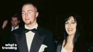 Cher smiling next to a man in a tuxedo at a nighttime event