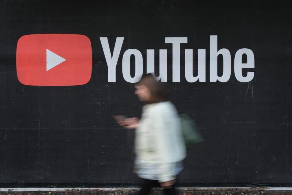 A young woman with a smartphone walks past a billboard advertisement for YouTube on September 27, 2019 in Berlin, Germany. YouTube has evolved as the world's largest platform for sharing video clips.