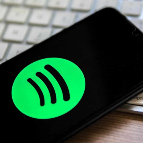 In this photo illustration, a Spotify logo seen displayed on a smartphone on top of a computer keyboard.