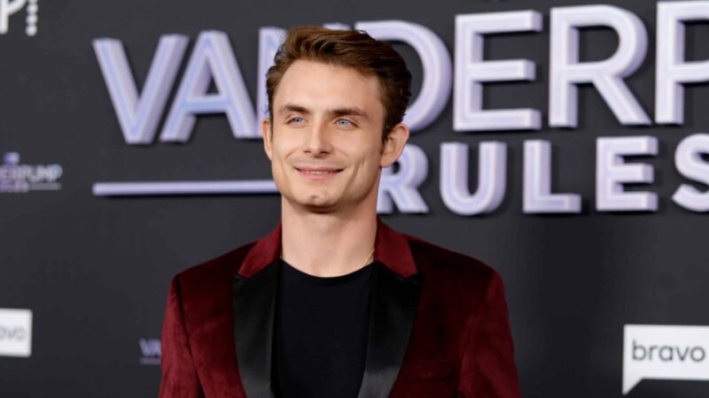 Actor Jacob Elordi smiling at the Vanderpump Rules premiere event wearing a burgundy velvet blazer.