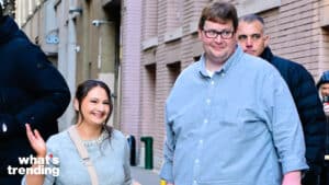 Smiling woman in gray sweater and man in light blue shirt walking on city street with brick buildings in background