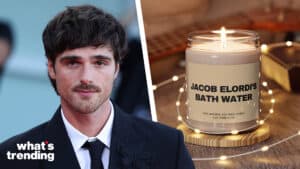 Actor Jacob Elordi in a suit next to a lit candle labeled "Jacob Elordi's Bath Water" by Lux Candle Co.