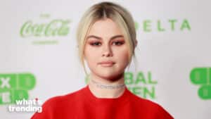 Selena Gomez wearing a red top and diamond choker at a Coca-Cola and Delta sponsored event.