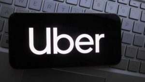 In this photo illustration, Uber logo is displayed on a smartphone with a workplace background.