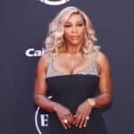 Serena Williams wearing a black and silver dress posing on the ESPYs red carpet.