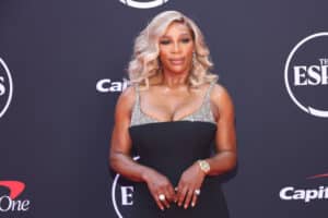 Serena Williams wearing a black and silver dress posing on the ESPYs red carpet.