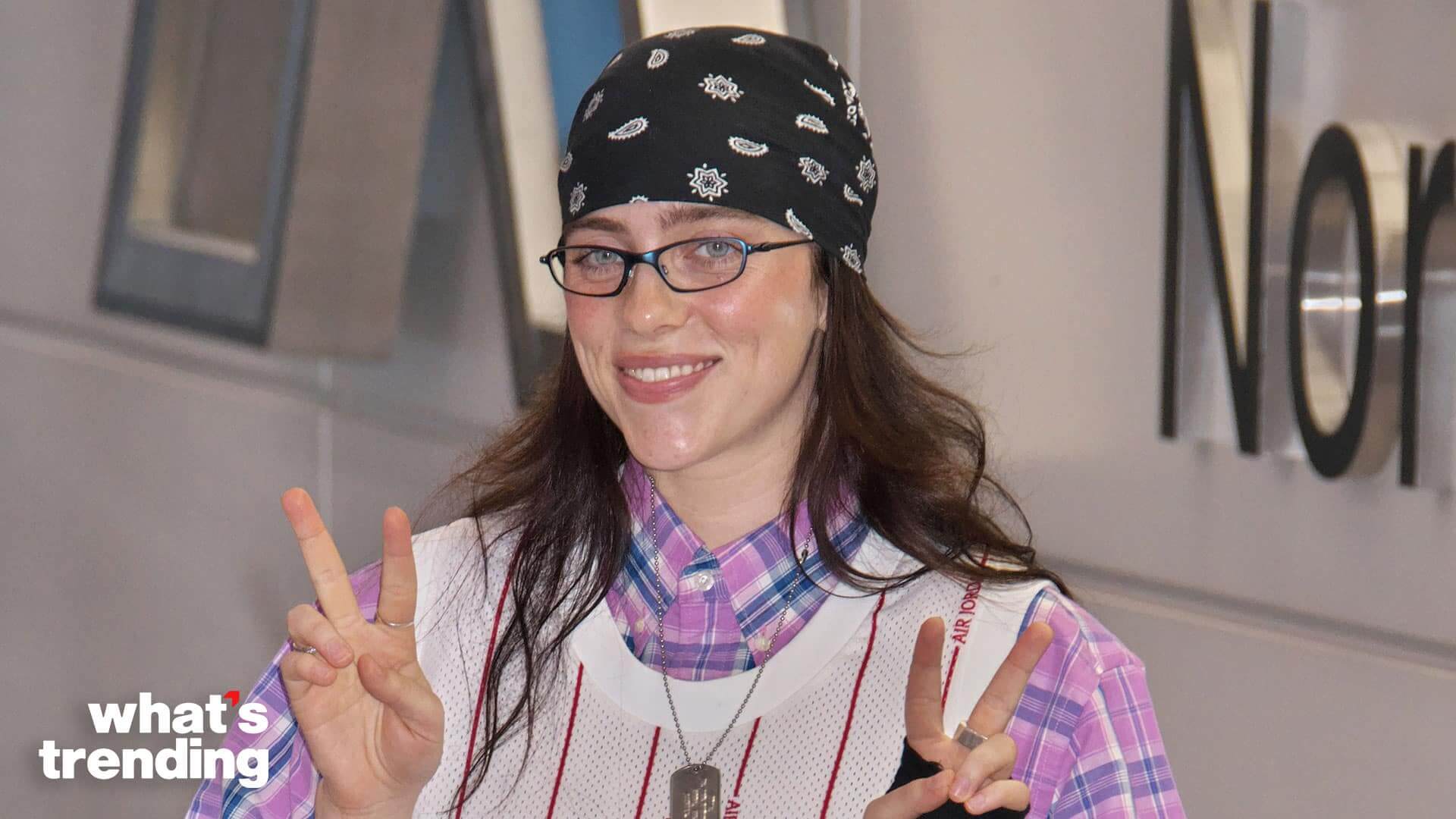 Person wearing glasses, a black bandana, and a white Air Jordan jersey making peace signs with both hands