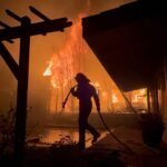 A Firefighter works to save a home during the Eaton fire outside of Los Angeles. Evacuation orders are in place after a fast moving brush fire broke out Tuesday night. Four fires are currently burning, Palisades, Eaton, Hurst and Woodley, all are 0% contained with two people killed and more than 1,000 structures burnt. Palisades has now become the most destructive in LA's history. Tens of thousands of people have been forced to evacuate their homes.