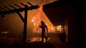 A Firefighter works to save a home during the Eaton fire outside of Los Angeles. Evacuation orders are in place after a fast moving brush fire broke out Tuesday night. Four fires are currently burning, Palisades, Eaton, Hurst and Woodley, all are 0% contained with two people killed and more than 1,000 structures burnt. Palisades has now become the most destructive in LA's history. Tens of thousands of people have been forced to evacuate their homes.